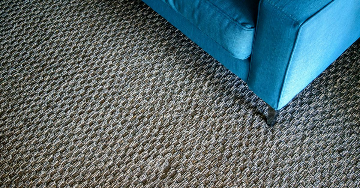 A modern blue sofa corner on a textured woven carpet, capturing a minimalist design.
