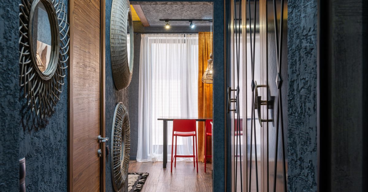 Room with table and chair against corridor with assorted decorative panels on wall in daylight at home